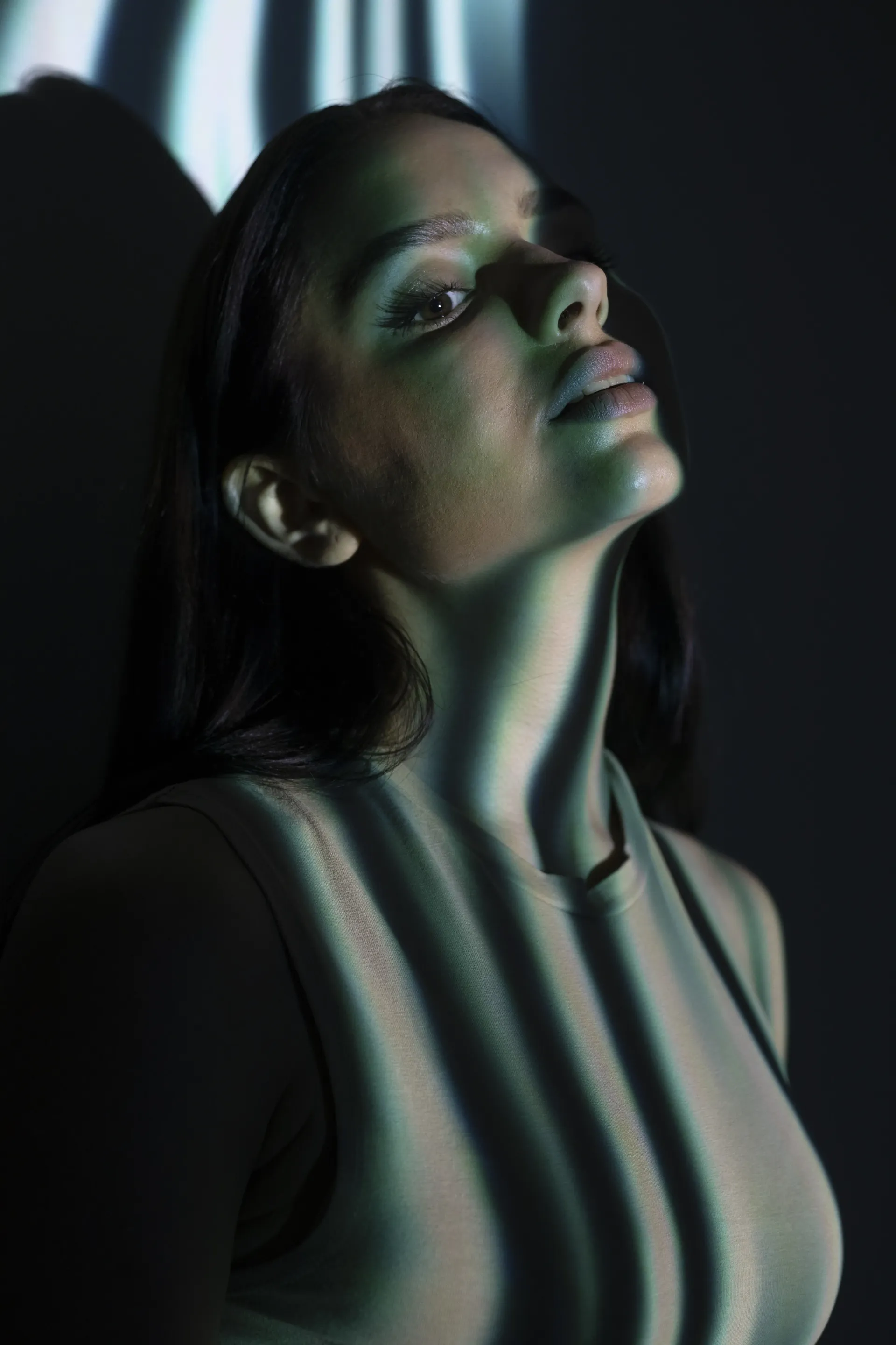 Moody side portrait of a young woman under artistic lighting, evoking mystery and desire